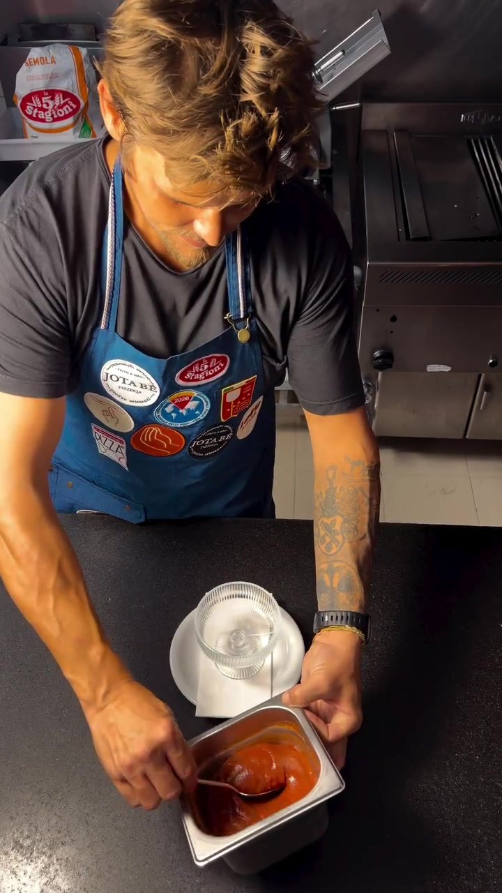 Pedro Mutz de avental azul com patches, na bancada da cozinha