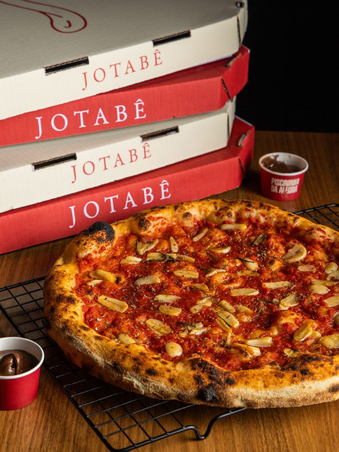 Pizza marinara da Jotabê em frente às caixas do delivery